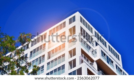 Eco architecture. Green tree and new apartment building. Exterior of a high modern multi-story apartment building - facade, windows and balconies. Royalty-Free Stock Photo #2363062077