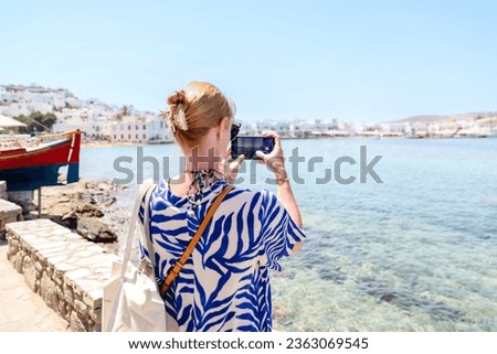 Mykonos, Greece - July 21, 2023: A blonde woman taking pictures in Mykonos Greece
