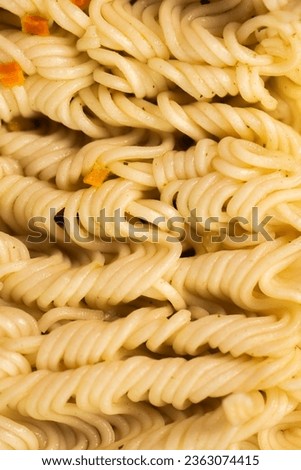 Macro photo of cooked instant noodles. The texture of noodles with pieces of vegetables and herbs.