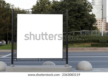 Blank horizontal large billboard in the city. Square with green leaves in the background. Mock-up.