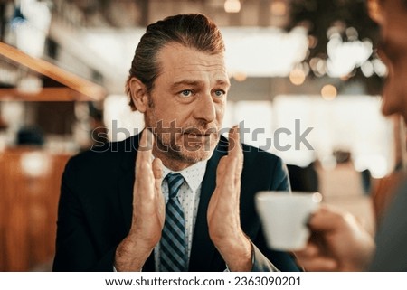 Middle aged businessman having a discussion with a coworker while having coffee in a cafe Royalty-Free Stock Photo #2363090201