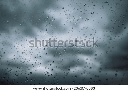 Window with small raindrops on the surface of a glass against a blue cloudy sky after a storm. Weather forecast. Rainy season. Fall or spring cold day. View of the sky from the window. Air concept. 