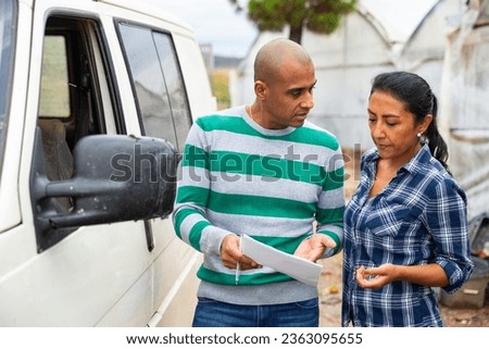 Portrait of latina male and female gardeners signing papers and discussing working process outside