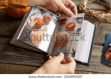 Hands put printed photos in picture album. Photo printing, Thanksgiving day memories, autumn concept.