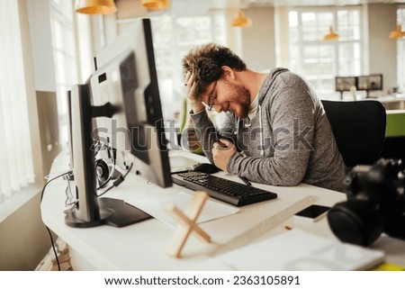 Young Caucasian office worker stressed after making a mistake on a project in a modern business office