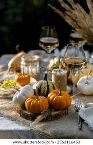 Fall still-life. Orange pumpkins, dry flowers and candles on linen tablecloth. Dinner table outdoors in the garden. Cozy autumn concept., simple handmade decoration, countryside style