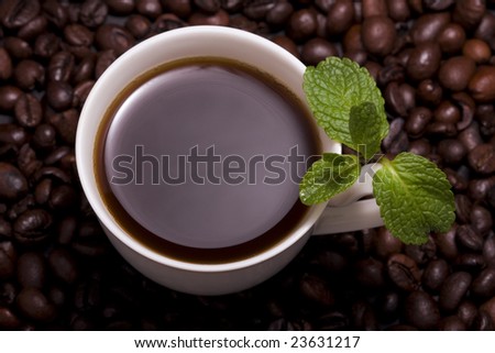 Image of a cup of coffee with mint, which is next to the dispersal of coffee