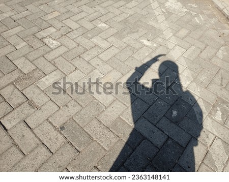 The shadow of a woman wearing a hijab covering her head due to exposure to sunlight. Shadow photography.