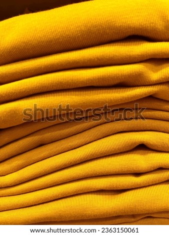 Close up yellow colored clothing top stacks fabric texture for fashion themed industry photography isolated on vertical ratio template background.