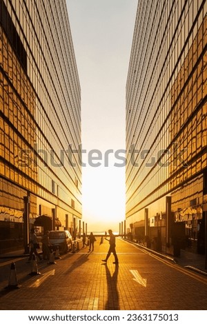 Silhouette of pedestrian under sunset in downtown district Royalty-Free Stock Photo #2363175013