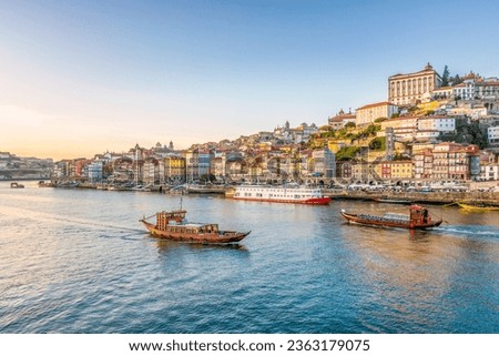 Scenic view of the city of Porto in Portugal in warm winter sunset light with boats and Douro river in foreground  Royalty-Free Stock Photo #2363179075