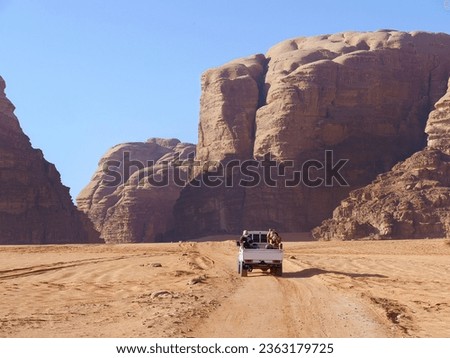 A pickup truck riding in Desert of Wadi Rum, red and orange sand dune landscape, UNESCO World Heritage site, Outdoor National Park, offroad adventure travel destination