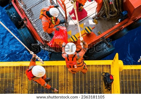 Workers on the rig jump overboard using ropes to return to their accommodations. Royalty-Free Stock Photo #2363181105