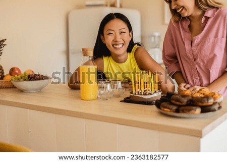 diverse friends celebrating birthday with cake with candles, asian woman smiling looking at camera