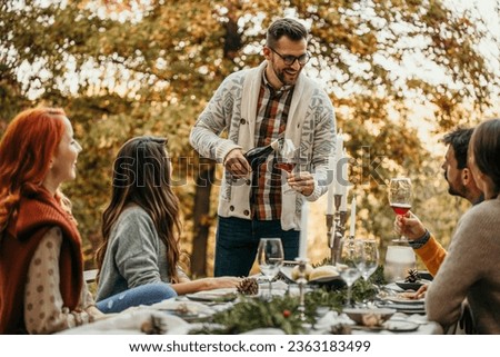 The essence of a memorable garden lunch, the host pouring a wine, and friends come together to create cherished moments in a picturesque outdoor setting.