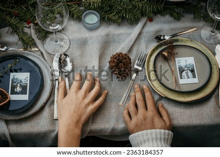Close up of a hands on a table with a plate and cutlery.