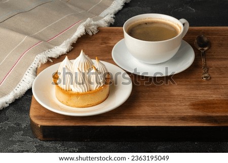 Meringue tart with coffee cup on dark gray background