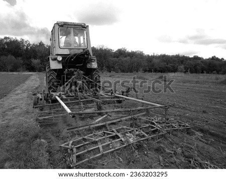 Plowed field by tractor in black soil on open countryside nature, tractor in plowed field, soil to growing tasty vegetables, organic plowed field under the clean dark sky is natural soil for tractor