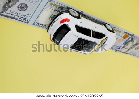 White toy car on money road on yellow background with copy space.