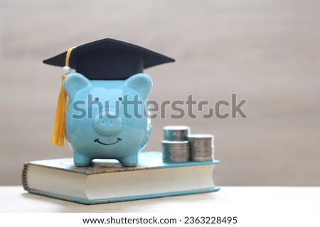 Graduation hat on blue piggy bank with stack of coins money on wooden background, Saving money for education concept  Royalty-Free Stock Photo #2363228495
