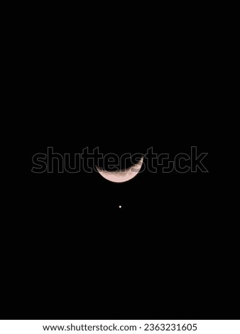 A crescent moon with Venus below it in the night sky