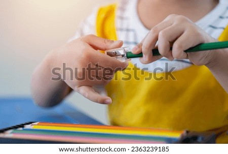 Young children hands using pencil sharpener for sharpening colored pencils. Education concept, selective focus. Royalty-Free Stock Photo #2363239185