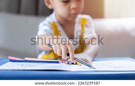 Selective focus of baby boy hands detail of a young children coloring drawing with multicolored pencils. Kids learning concept.