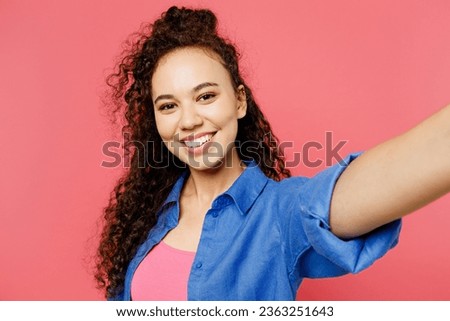 Close up young fun woman of African American ethnicity she wear blue shirt casual clothes doing selfie shot pov on mobile cell phone isolated on plain pastel pink background studio. Lifestyle concept