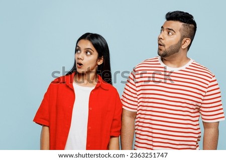 Young shocked surprised astonished couple two friends family Indian man woman wearing red casual clothes t-shirts look aside on area together isolated on pastel plain light blue cyan color background