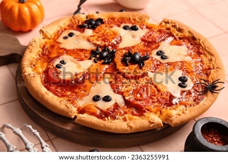 Wooden board with tasty pizza for Halloween celebration on beige tile background