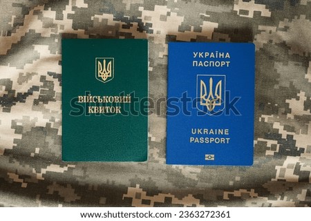 Translation: "military id". Ukrainian passport and military doc on camouflage pixel background. Mobilization, travel, law