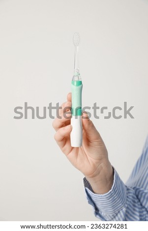 Woman holding electric toothbrush on white background, closeup