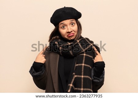 hispanic woman with a bad attitude looking proud and aggressive, pointing upwards or making fun sign with hands
