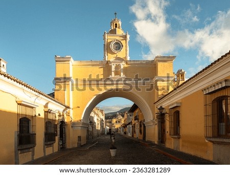 The famous arch of Santa Catalina in downtown Antigua, Guatemala and a view of the Volcano de Agua behind Royalty-Free Stock Photo #2363281289