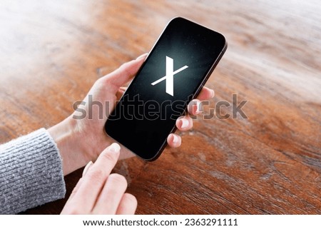 Person holding mobile phone with a letter X on the screen Royalty-Free Stock Photo #2363291111