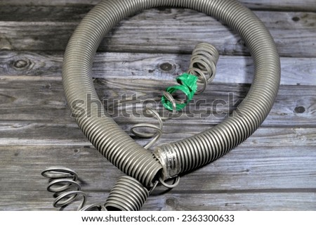 A broken flexible hose from a vacuum cleaner, substandard materials and maintenance services concept, a vacuum cleaner is an electrical house machine that collects dust and dirt by suction pressure Royalty-Free Stock Photo #2363300633
