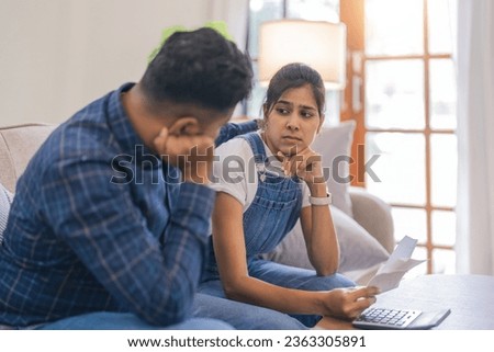 Young couple indian calculate the bill together, have serious looks, dressed in casual wear, plan their budget, paperwork, busy preparing financial report Royalty-Free Stock Photo #2363305891