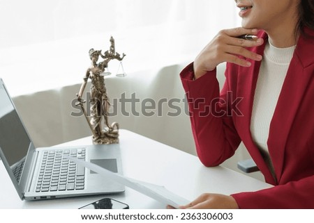 Attorney's office. Goddess of justice with scales and lawyer working on laptop Law, advice and justice concept Lawyer reads contract Young female lawyer or lawyer working in the office