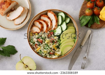 A nourishing lunch of couscous, cherry tomatoes, bell pepper, parsley, grilled chicken slices, fresh cucumber, and green apple Royalty-Free Stock Photo #2363308189
