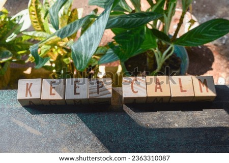 Photo of words with wooden block objects arranged into the word "KEEP CALM" in English
