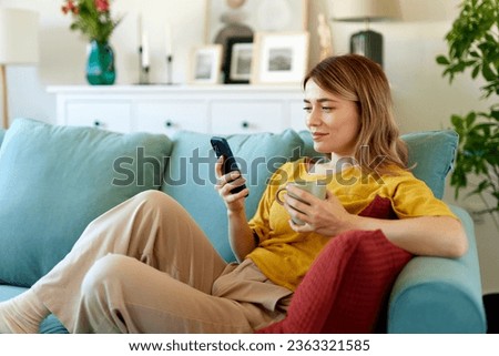 Woman using smartphone while drinking coffee at her home in the morning Royalty-Free Stock Photo #2363321585