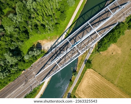 An awe-inspiring aerial perspective of a steel railroad bridge gracefully spanning over a serene river or canal. The intricate design and engineering marvel of this bridge provide a striking contrast