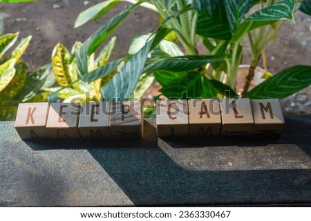 Photo of words with wooden block objects arranged into the word "KEEP CALM" in English