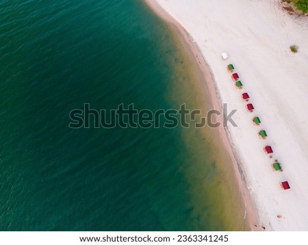 Drone shot of the beach stones tip, a sandy beach with colorful sun shades at the shore of a river with turquoise and clear water: Praia da Ponta de Pedras between Alter do Chão and Santarém in Brasil Royalty-Free Stock Photo #2363341245