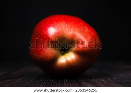 Red apple on a rustic table under dark lighting. close-up