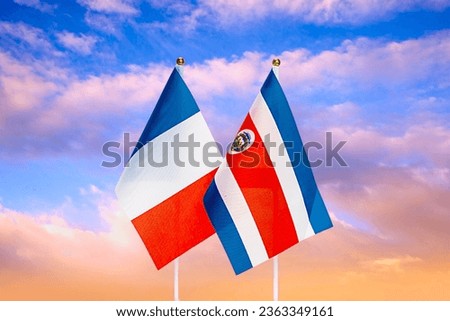 National flags of France and Cosia Rica against the sky at sunset. Flags.