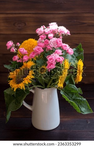 Autumn bouquet of flowers in a vase on a wooden background. Yellow sunflowers and pink roses, greeting card