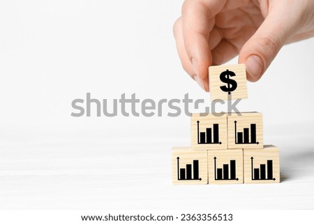 Woman putting cube with dollar sign on other ones with charts against white background, closeup