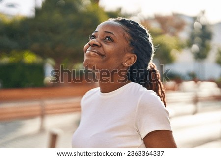 African american woman smiling confident looking to the sky at street