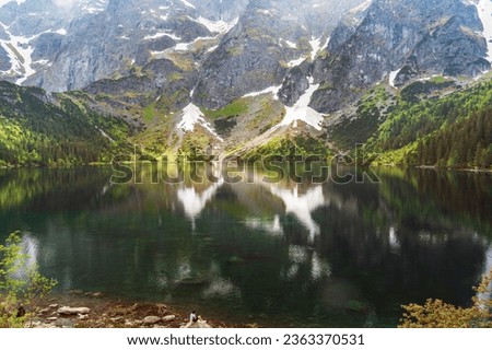 A young girl looks in awe at the stunning view of Morskie Oko Lake in the Polish Tatras National Park, clear waters reflect the mountains and forests, creating a mesmerizing picture of natural beauty